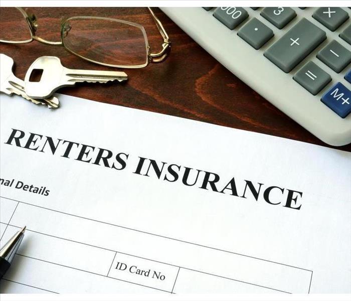 There is a white paper that says Renters Insurance, there are two keys, a calculator, a pair of glasses and a pen